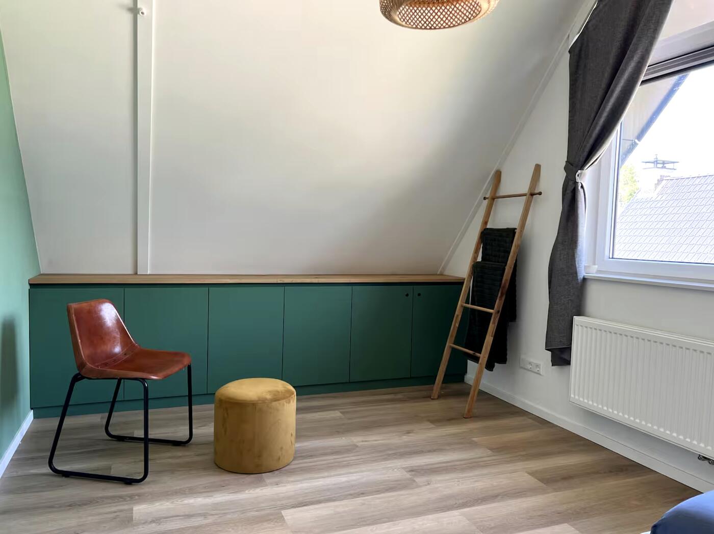 Overzicht van de voorkamer met stoel, poef en kastenwand