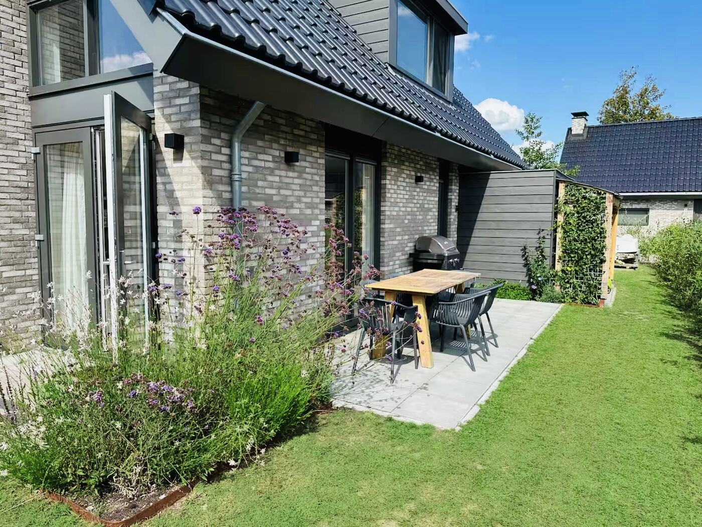 Zijterras met eettafel en barbecue naast het huis